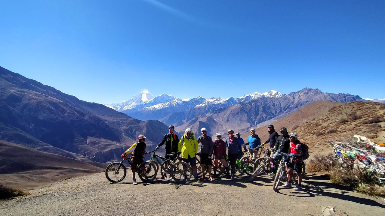Group of mountain bikers are posing for a picture at Lupra pass in Mustang with their bikes and the view of Dhaulagiri on the background.