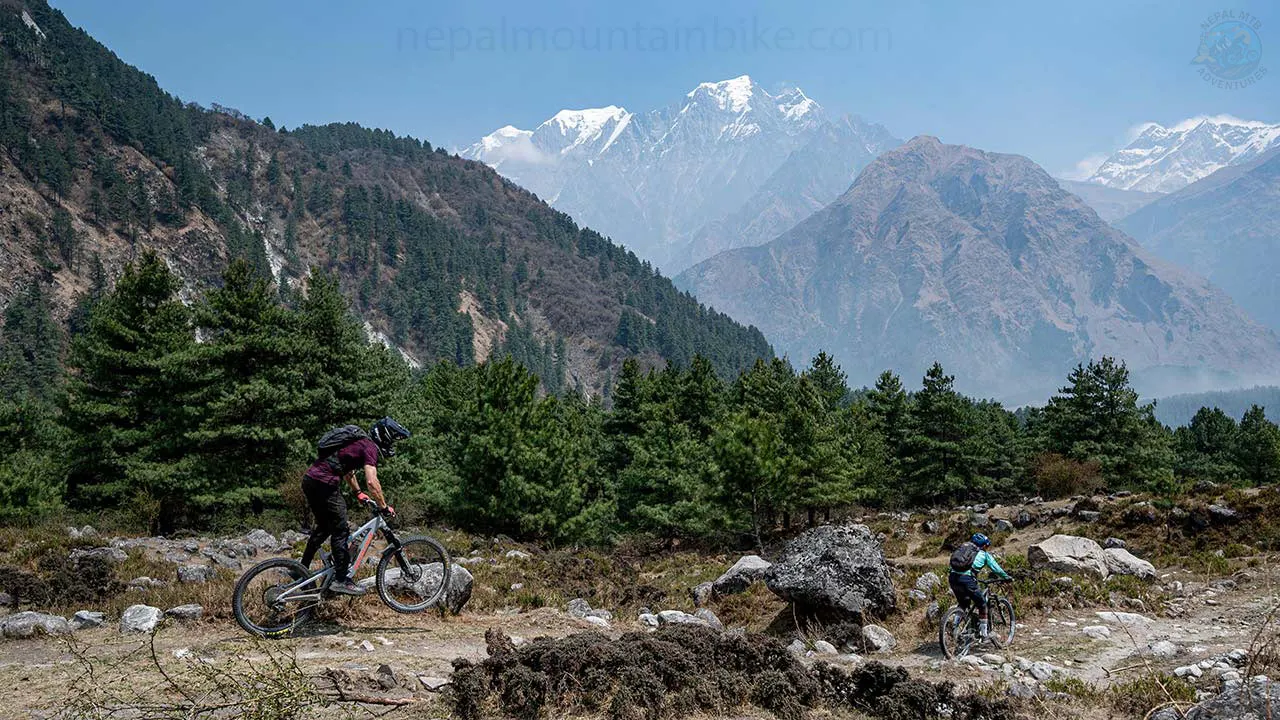 Mountain bikers are riding the techy singletrack in Kalopani with the view of Nilgiri and Annapurna I during Nepal Himalayan guided Enduro tour.