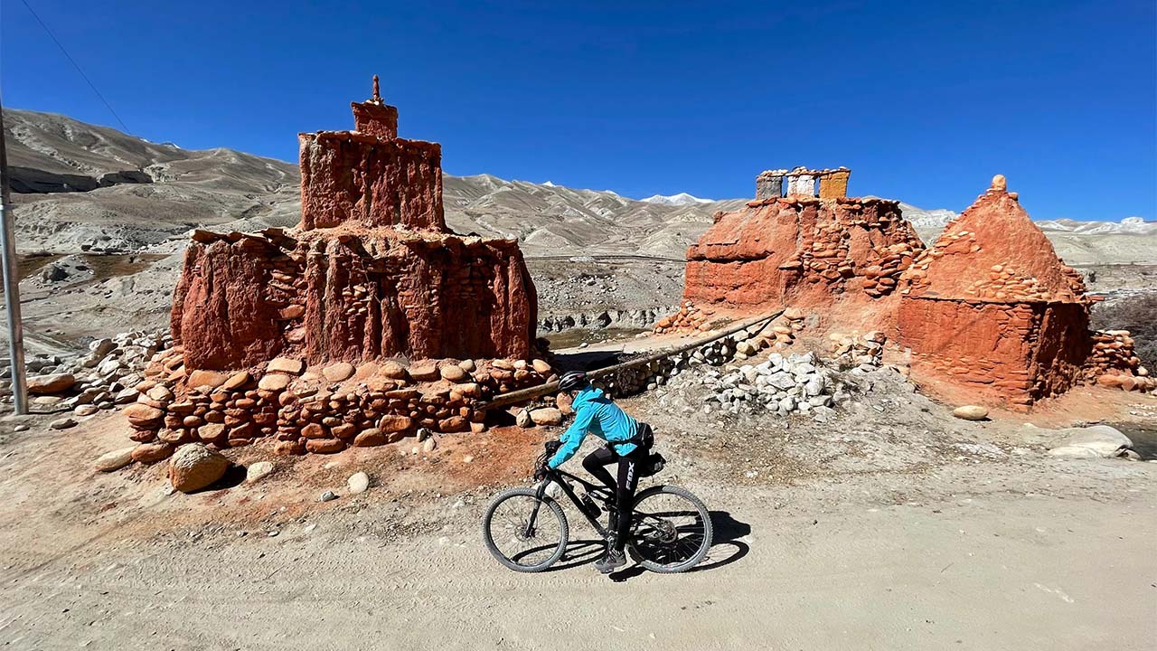 A biker rides his bike on the side of Ancient monasteries of Upper Mustang.