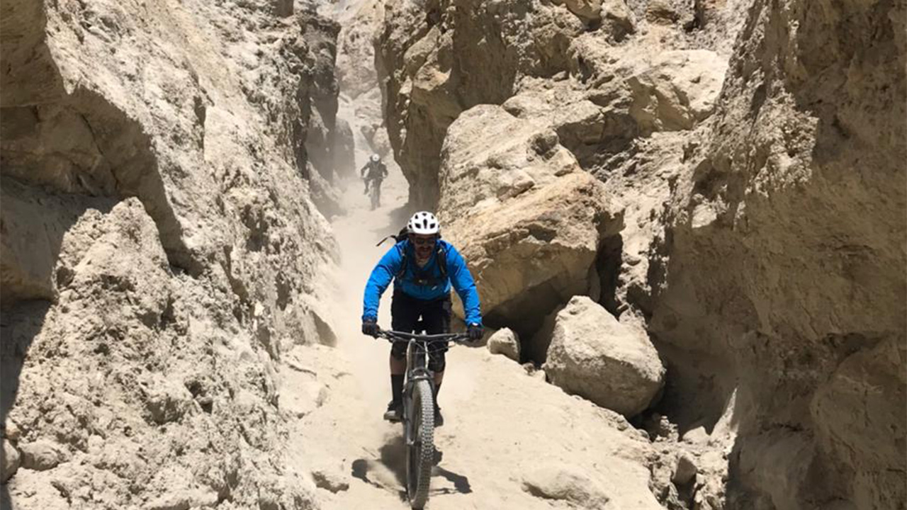 Two mountain bikers are rolling down a narrow trench during their off-the-beaten route biking in Upper Mustang.